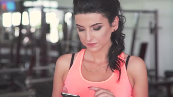 Chica joven usando el teléfono en el gimnasio moderno — Vídeos de Stock