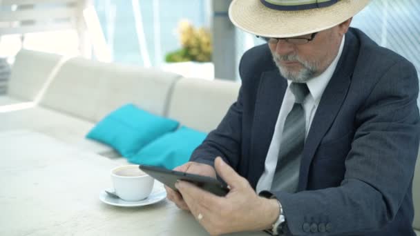 Viejo hombre de negocios usando la tableta y beber café en la cafetería. 4K — Vídeos de Stock