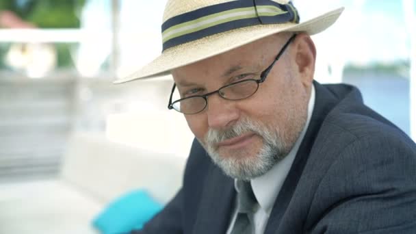 Retrato del anciano con sombrero y gafas sonriendo y asintiendo a cámara. 4K — Vídeo de stock