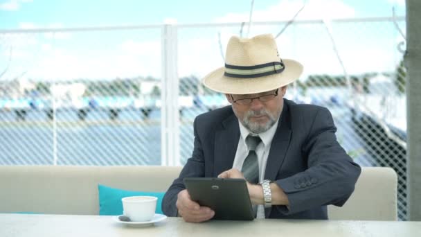 Vieil homme d'affaires utilisant une tablette et regardant la montre-bracelet à la table. 4K — Video