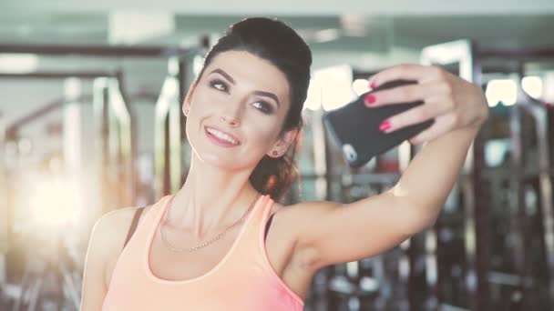 Chica glamurosa tomando selfies en el gimnasio. Movimiento lento — Vídeo de stock