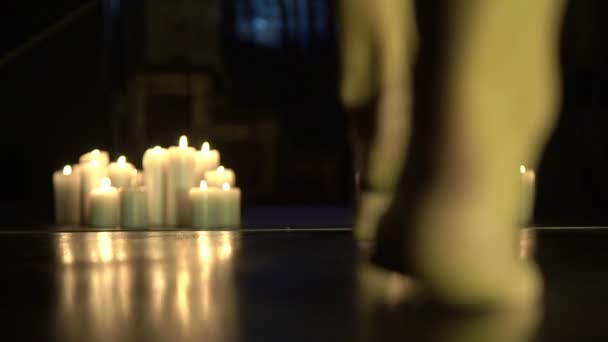 Элегантная женщина голыми ногами идет между горящими свечами в темной комнате — стоковое видео