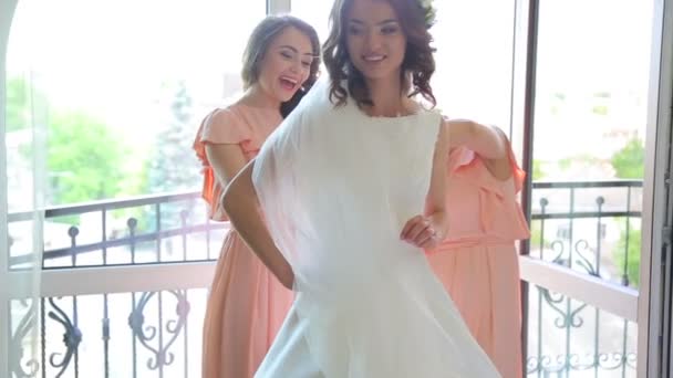 Lustige beste Freunde helfen beim Tragen des Hochzeitskleides auf dem Balkon — Stockvideo