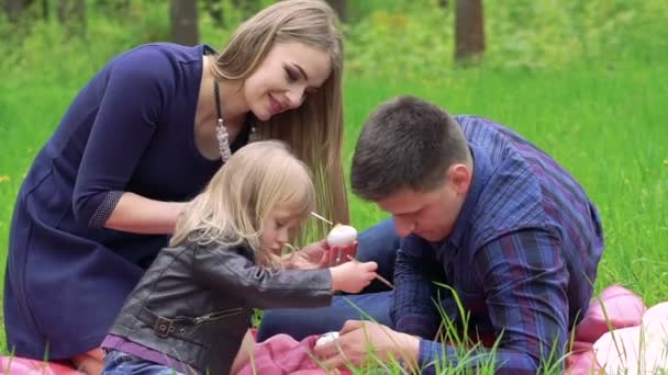 Щасливі батьки з бабіром малюють яйця на траві в парку — стокове відео