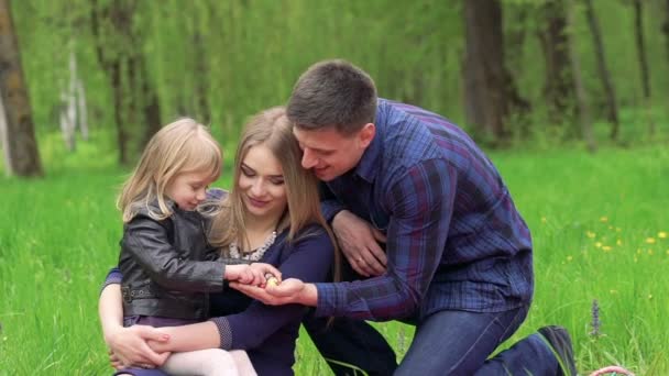 Gelukkige ouders met baby in het park bedrijf paaseieren — Stockvideo