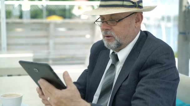 Старый бизнесмен разговаривает по интернету с планшетом. 4K — стоковое видео