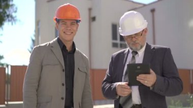 Olgun ve genç adam kameraya gülümseyen ve başını sallayarak kask içinde. 4k