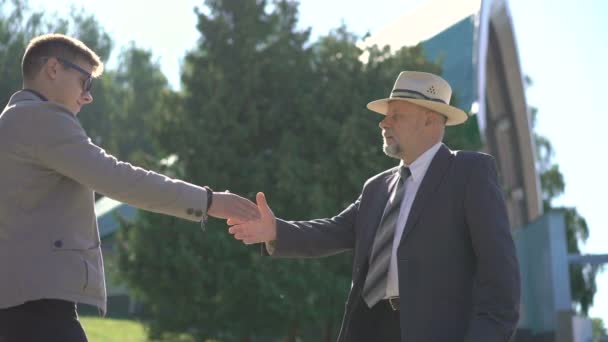 Two businessmen shaking hands and speaking outdoor. 4K — Stock Video