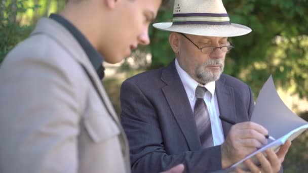 Trabajadores viejos y jóvenes escribiendo dowm en cuaderno en la calle. 4K — Vídeos de Stock