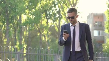 Telefon ile sokakta siyah gider giymiş kendinden emin ve tehlikeli görünümlü bir adam