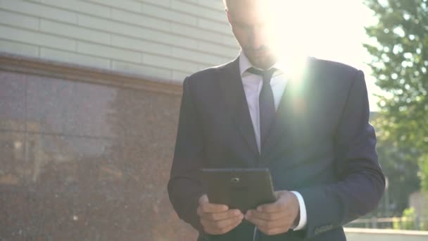 Бизнесмен использует планшет на открытом воздухе на рассвете и ослепительно. 4K — стоковое видео
