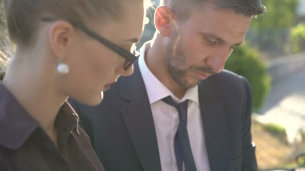 Woman and man working with tablet and laughing on the bench outdoor. 4K — Stock Video