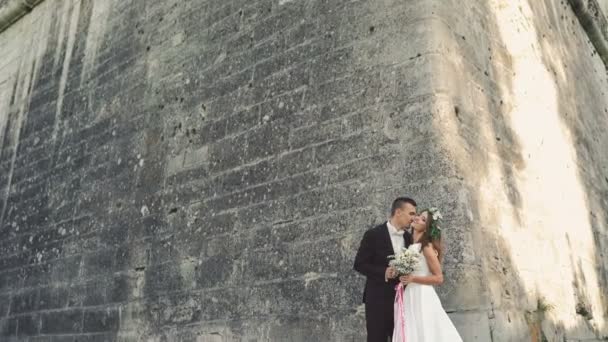 Hermosa pareja de boda abrazando cerca de la pared del castillo 4K — Vídeo de stock