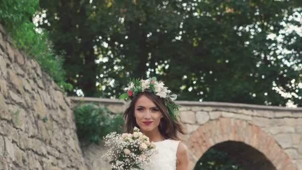 Felice sposa in posa corona con bouquet da sposa vicino al castello. Lentamente. — Video Stock