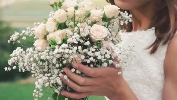 Gros plan de la mariée reniflant bouquet et souriant dans le champ. Doucement. — Video