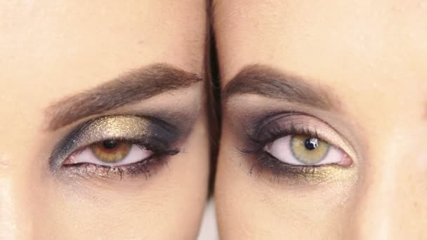 Close up on eyes of two girls faces next to one another with make up. Slowly — Stock Video