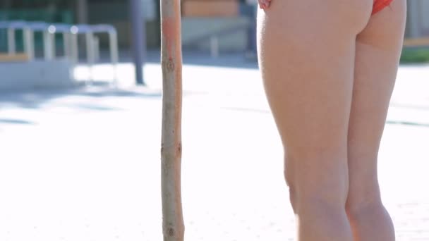 Menina sexy em estandes maiô em pose perto do pólo de madeira ao ar livre. Devagar. — Vídeo de Stock