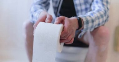 Adamın elinde tuvalet kağıdı rulosuyla kabızlığı var.