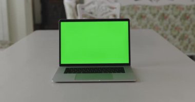 Yeşil ekranlı açık dizüstü bilgisayar masadaki kameranın önünde.