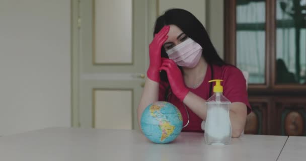 Kobieta-lekarz w masce i rękawicach dezynfekujących ręce środkiem dezynfekującym w pobliżu globu — Wideo stockowe