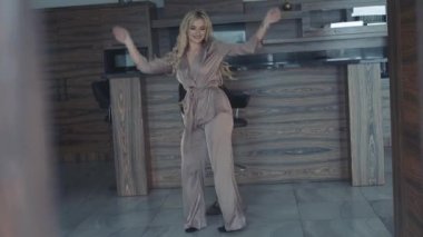 Kaygısız sarışın kameraya dans eder ve bar taburesinde döner.
