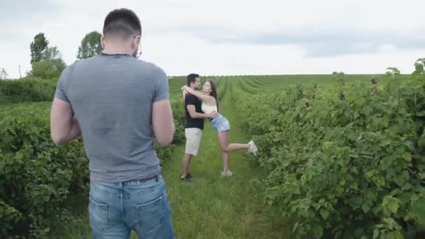 Szczęśliwa młoda para ma sesję zdjęciową wśród plantacji porzeczek — Wideo stockowe