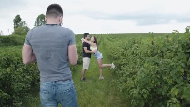 Feliz pareja joven teniendo fotosesión entre plantación de grosella — Vídeos de Stock