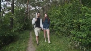 Aşık mutlu çift ormanda öpücüklerle kucaklaşarak yürüyor.