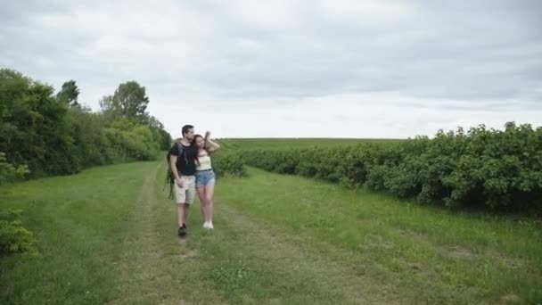 Lovely, happy couple with rucksacks walks in embraces on nature. 4K — Stock Video