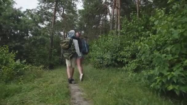 Aşık mutlu çift ormanda öpücüklerle kucaklaşarak yürüyor. — Stok video