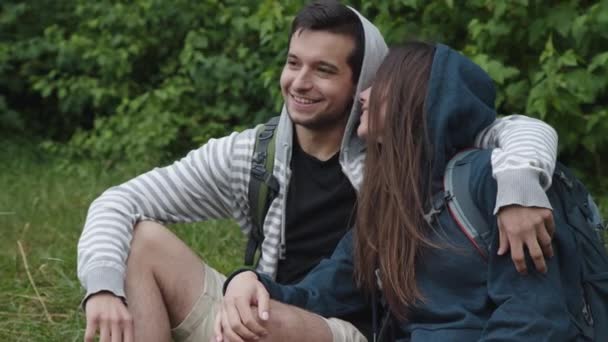 Ρομαντικό ζευγάρι στην αγάπη χαλαρώνοντας αγκαλιάζει στο γρασίδι και χαμογελώντας — Αρχείο Βίντεο
