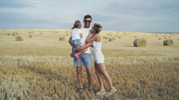 Портрет молодих батьків зі своєю маленькою донькою веселяться серед поля — стокове відео