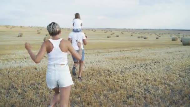 Happy mother overtaking her husband with daughter in field — Stock Video