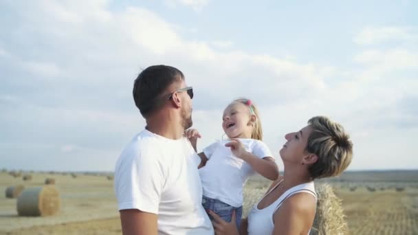 Padres felices jugando con su hija pequeña en haycock en el campo — Vídeos de Stock