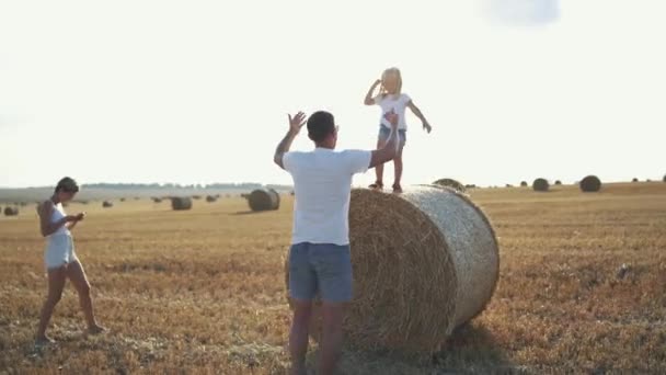 Famiglia felice divertirsi nel campo fieno cazzi, figlia saltando in mano — Video Stock