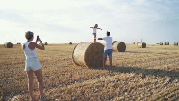 Madre felice scattare foto di sua figlia che salta nelle mani del padre — Video Stock