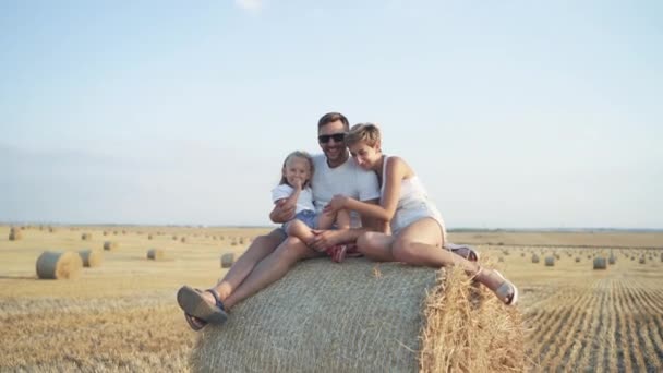 Retrato de padres felices con hija sentada en el pajar en el campo — Vídeos de Stock