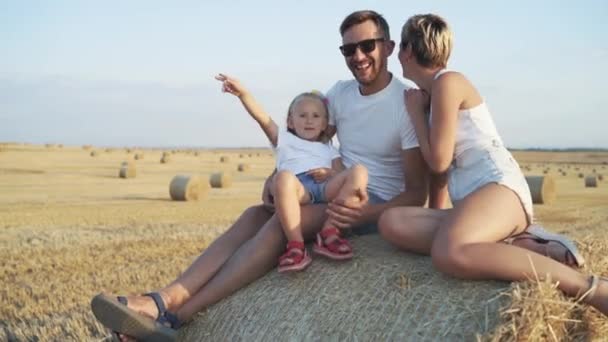 Mutlu ebeveynler, samanlıkta rahatlarken çocuğuyla birlikte seviniyor. — Stok video
