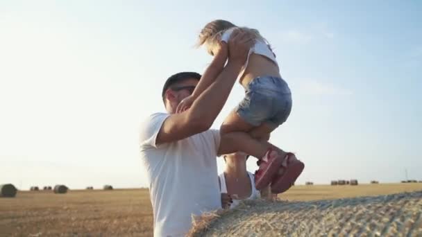 Счастливые родители играют с маленькой дочерью на сене в поле — стоковое видео