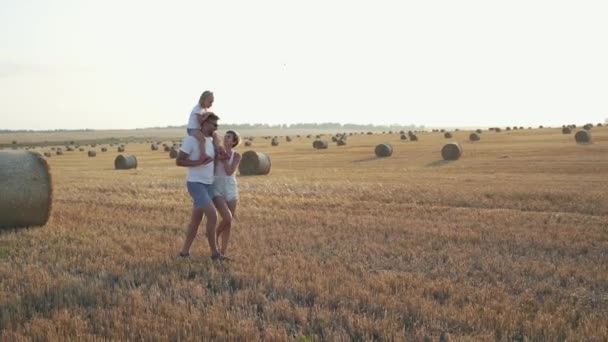 Bella famiglia con bambina sulle spalle che cammina in un campo spazioso. 4K — Video Stock