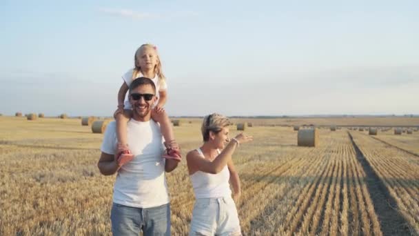 Linda família com filhinha olhando ao redor no campo durante uma caminhada — Vídeo de Stock