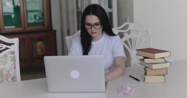Étudiante tapant sur un ordinateur portable pendant ses études à table dans la chambre — Video