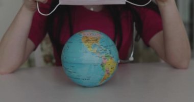 Covering the globe with a medical mask and grasp it by female hands at camera