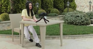 Pretty blogger talks on video camera online and holds medical mask in garden