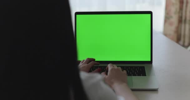 Kobieta wpisując na klawiaturze laptopa z zielonym ekranem na stole — Wideo stockowe