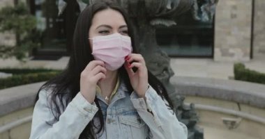 Happy girl in garden undresses medical mask and smiles at camera with relief