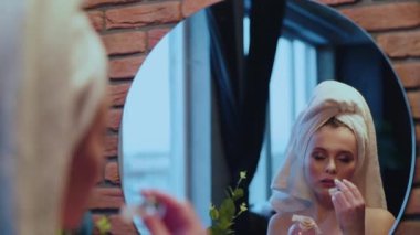 Havlu giymiş kadın aynadaki krem kokulu.