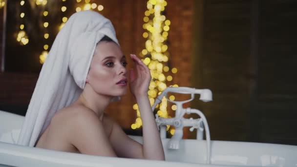 Влажная леди позирует перед камерой в ванне с полотенцем на голове Медленно — стоковое видео