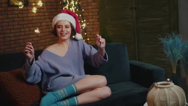 Ευτυχισμένο κορίτσι σε ζεστό φορούν χαλάρωση στον καναπέ με sparklers — Αρχείο Βίντεο