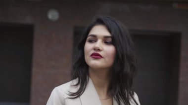 Çekici makyajlı tutkulu esmer düşünceli bir şekilde açık havada poz veriyor.